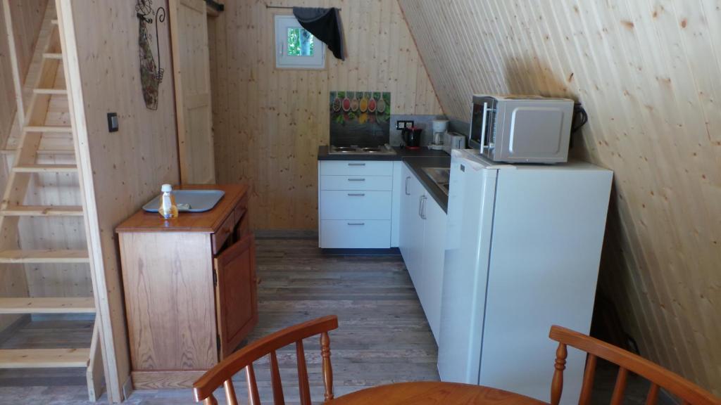 a kitchen with a white refrigerator and a microwave at SARL A Faire à Cheval in Parzac