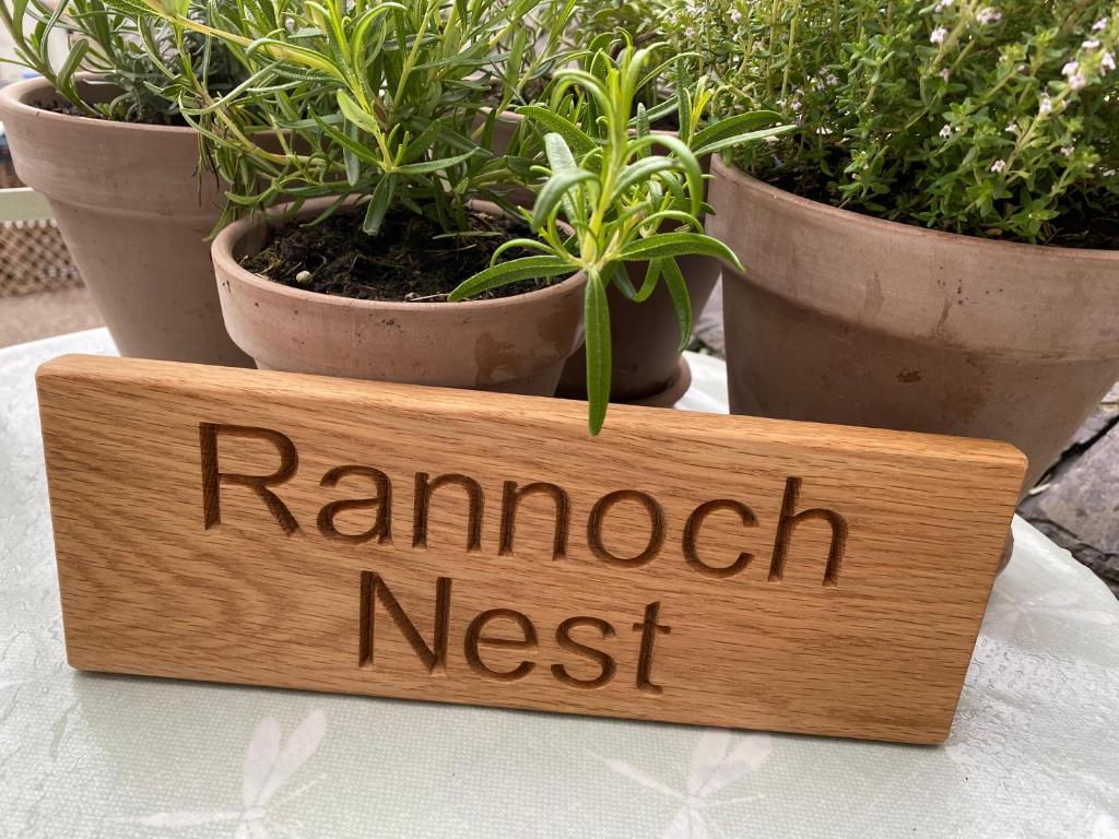 a wooden sign on a table with plants at The Rannoch Nest, Kinloch Rannoch in Kinloch Rannoch