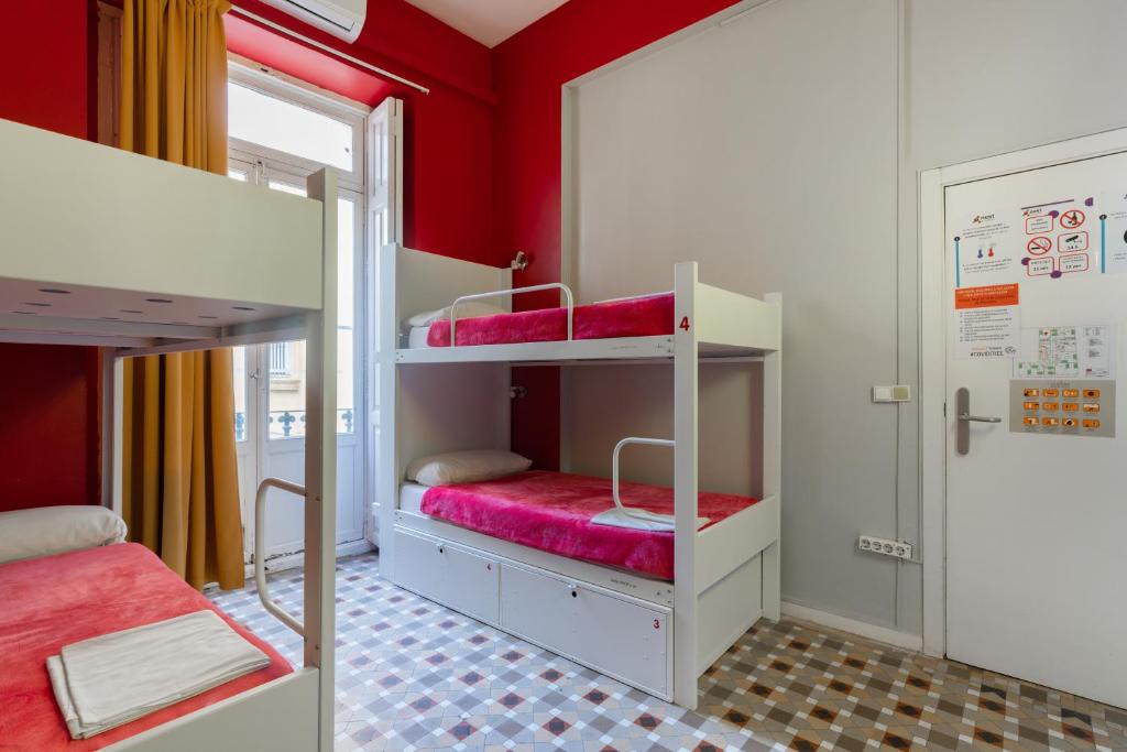 バレンシアにあるレッド ネスト ホステルの赤い壁のドミトリールームの二段ベッド2台
