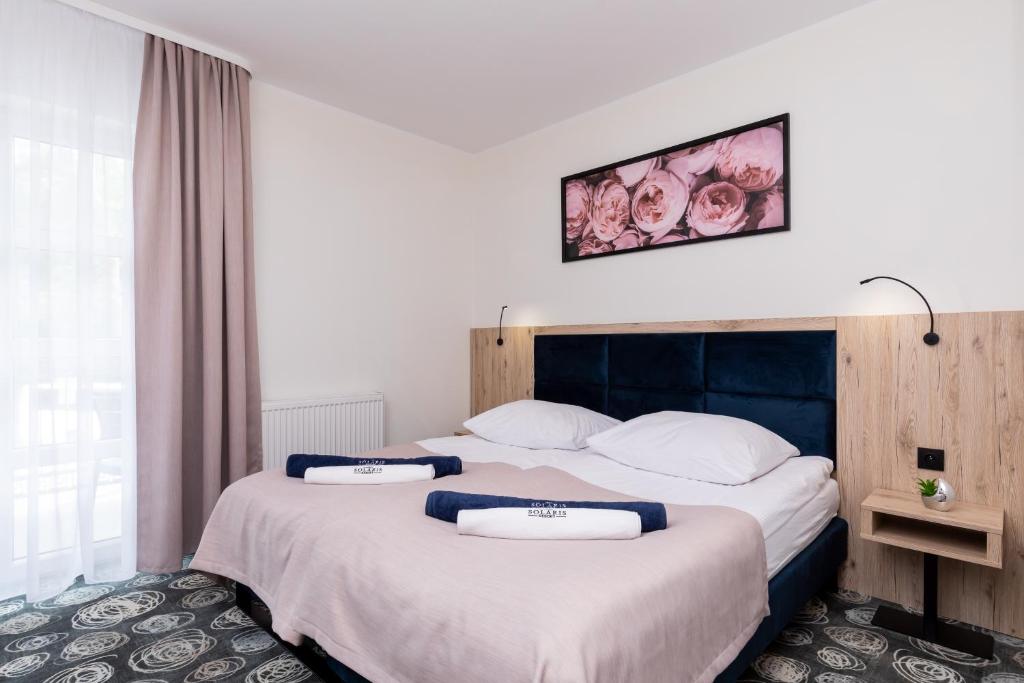 two twin beds in a hotel room with a picture on the wall at Villa Solaris in Pobierowo