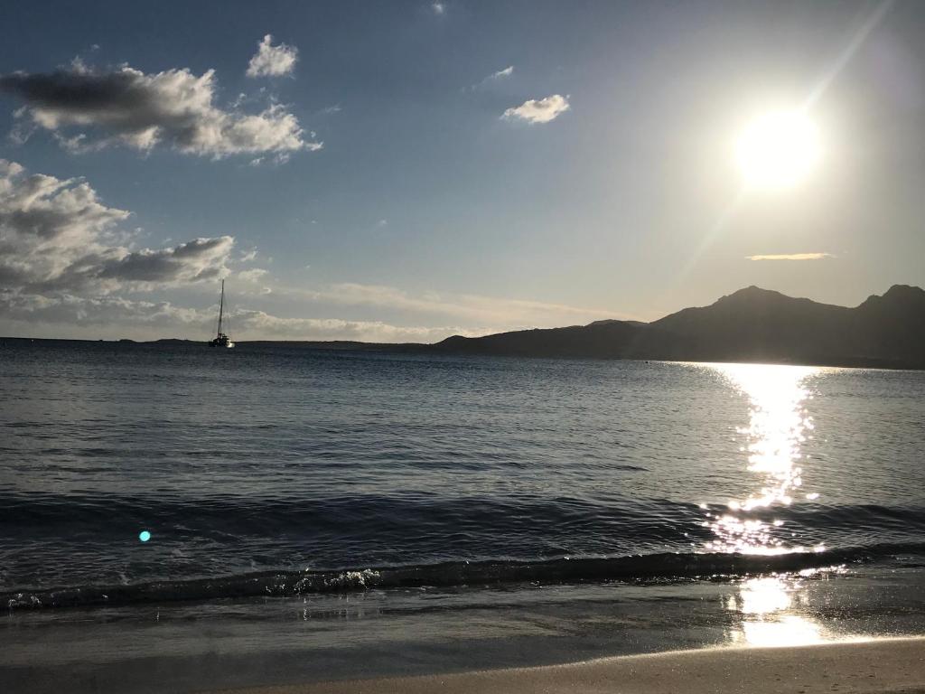 una playa con el sol brillando en el agua en Duplex rénové les pieds dans l'eau, en Calvi