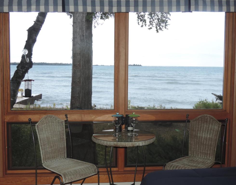 een tafel en stoelen in een kamer met uitzicht op de oceaan bij Square Rigger Harbor Motel in Baileys Harbor