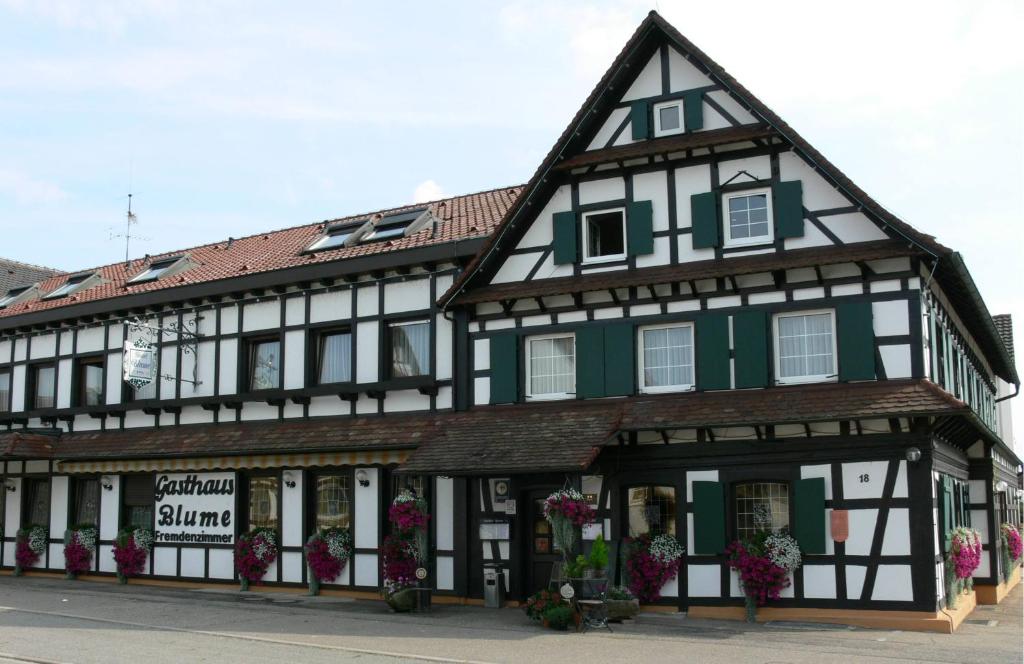 un bâtiment noir et blanc avec des fleurs devant lui dans l'établissement Hotel Landgasthof Blume, à Lichtenau