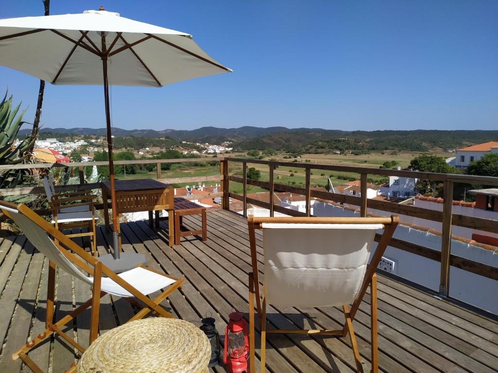 een terras met stoelen, een parasol en een tafel bij Casa Pe do Castelo in Aljezur