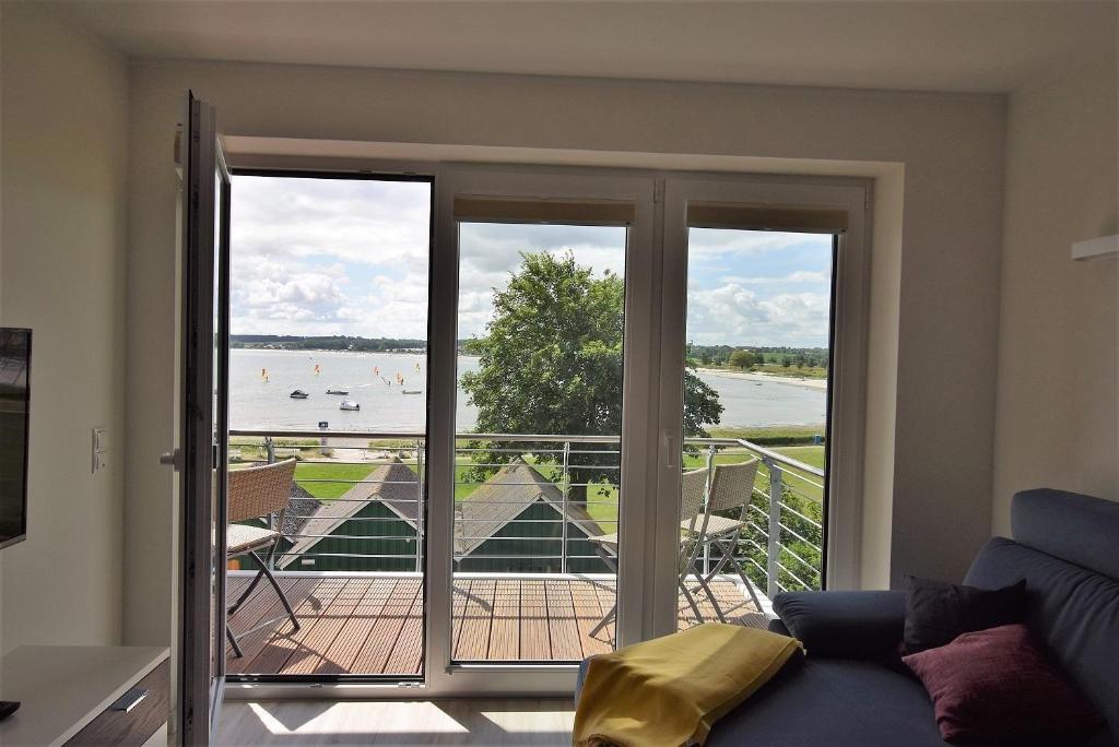 a living room with doors to a balcony with people on the water at Meeresblick-Strandperle-Haus-2-WE-24 in Hohwacht