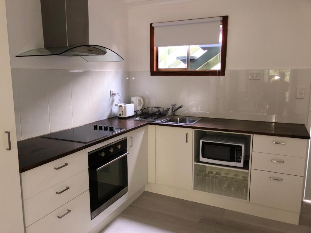 a kitchen with white cabinets and a black counter top at Airlie Getaway Unit 3 in Cannonvale