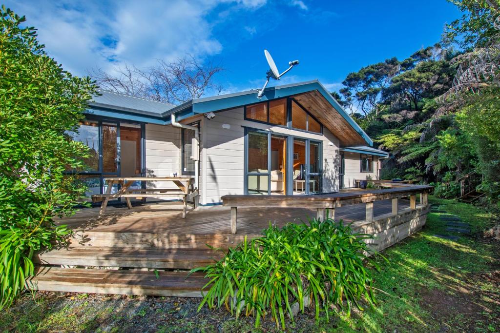 een klein wit huis met een houten terras bij Pearl Retreat - Mangawhai Heads Holiday Home in Mangawhai