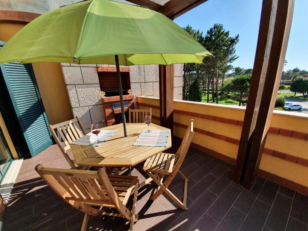 a wooden table and chairs with a green umbrella at Big Fish 1 - Charming Beach Apartment in Praia de Mira