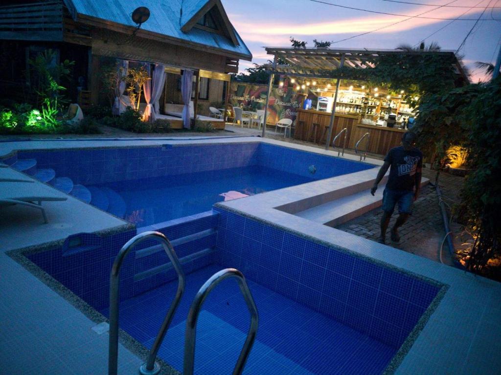 Ein Mann stand nachts neben einem Schwimmbad. in der Unterkunft Descanso En Paraiso Resort in Siquijor