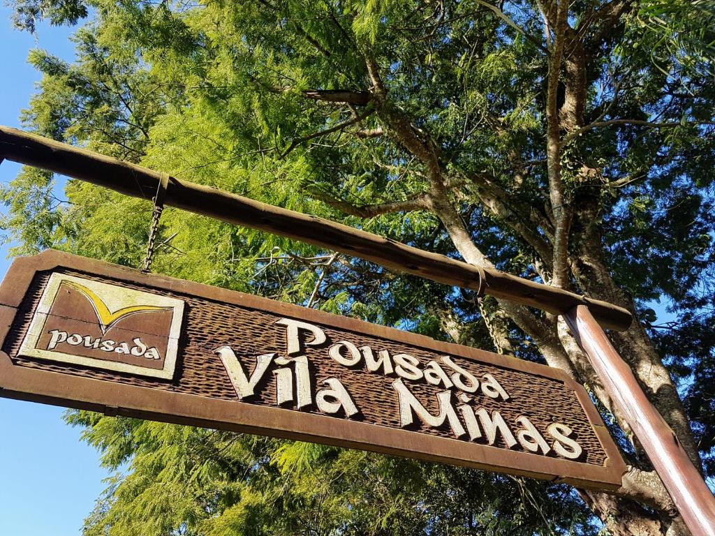 a sign for a pocomoke villas in front of a tree at Pousada Vila Minas in Itanhandu
