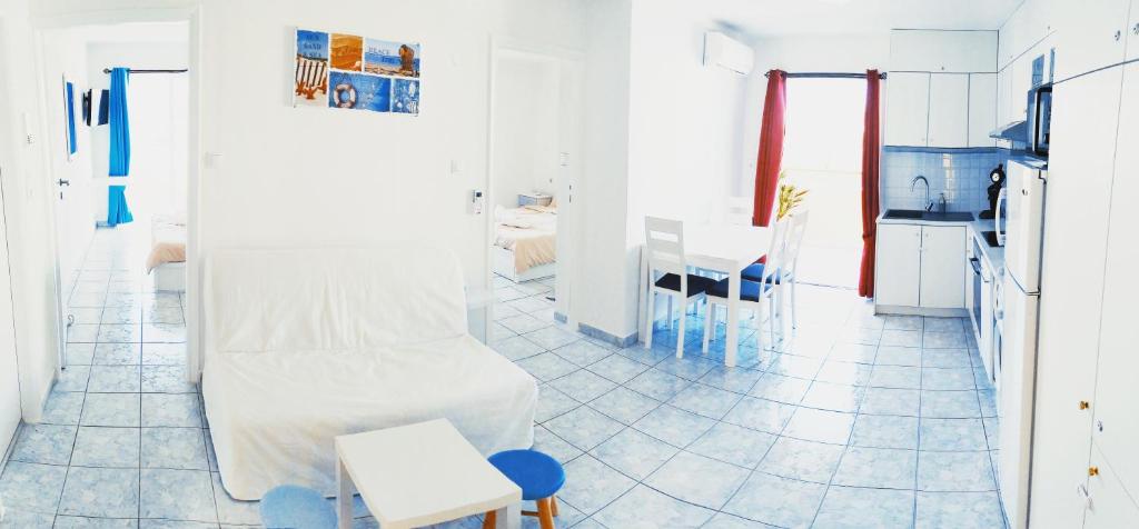 a white kitchen with a white couch and a table at Domus Dulcis Domus in Hersonissos