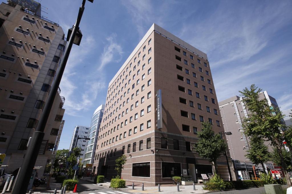 ein hohes Gebäude mitten in einer Stadt in der Unterkunft Court Hotel Shin-Yokohama in Yokohama