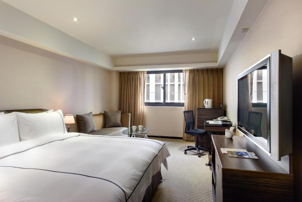 台北市にあるK ホテル タイペイの大きなベッドとデスクが備わるホテルルームです。