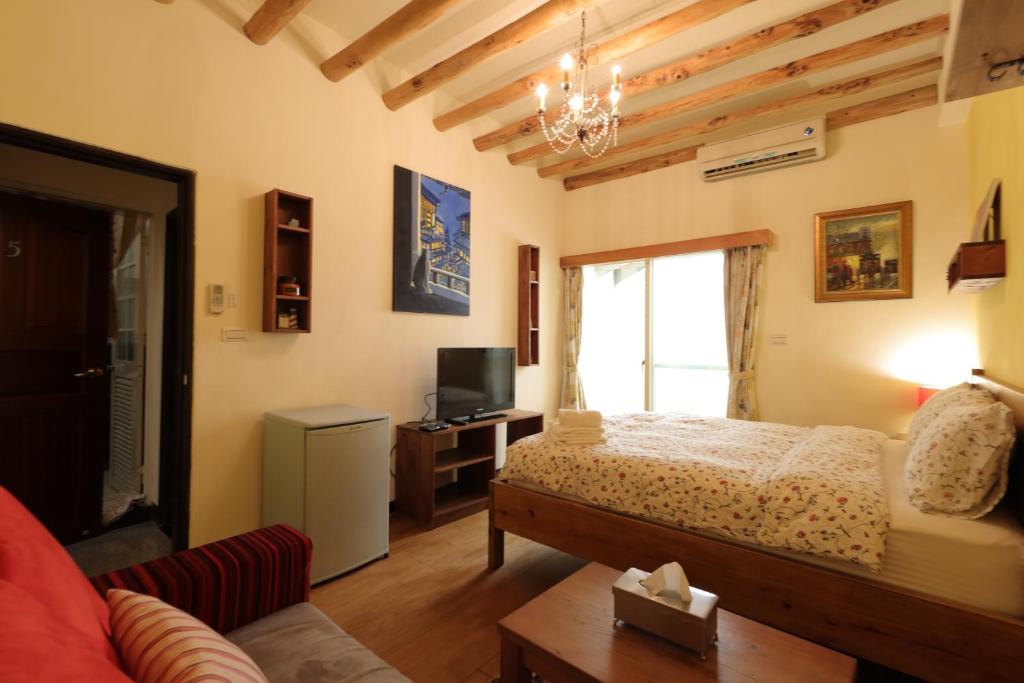 a bedroom with a bed and a couch and a tv at Seville Countrified B&amp;B in Hualien City