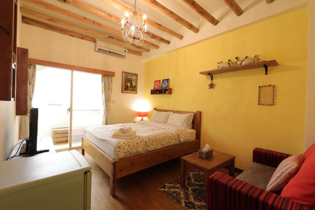 a bedroom with a bed and a living room at Seville Countrified B&amp;B in Hualien City