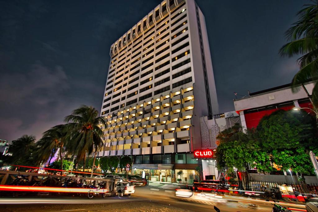 a tall building at night with a street in front of it at Jayakarta Hotel Jakarta in Jakarta