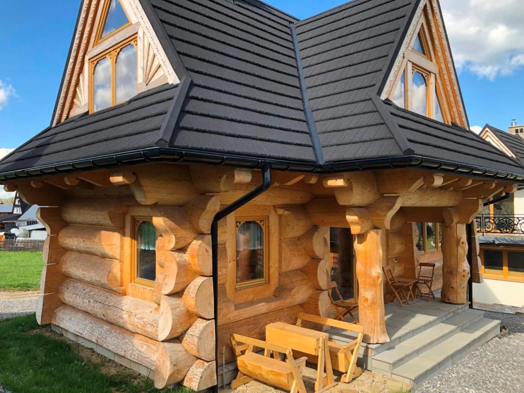 a log cabin with a black roof at Osada Witów - dom „Dziewięćsił” in Witów