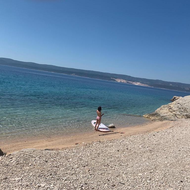 a woman standing on a beach with a surfboard at Villa Sanja in Mimice