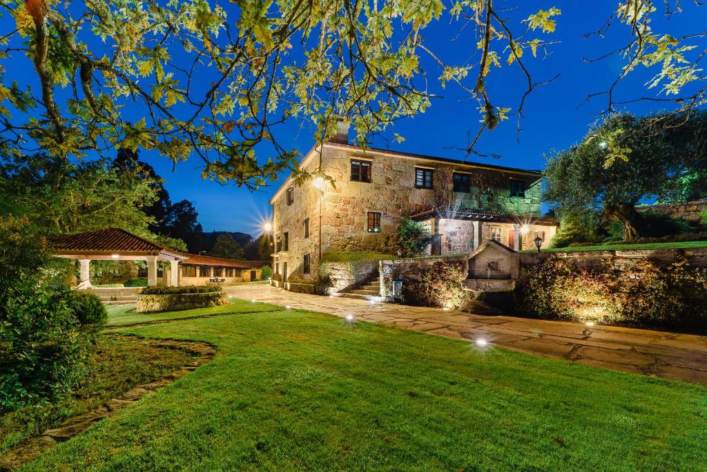 un domaine la nuit avec des lumières sur la pelouse dans l'établissement Casal dos Celenis, à Caldas de Reis