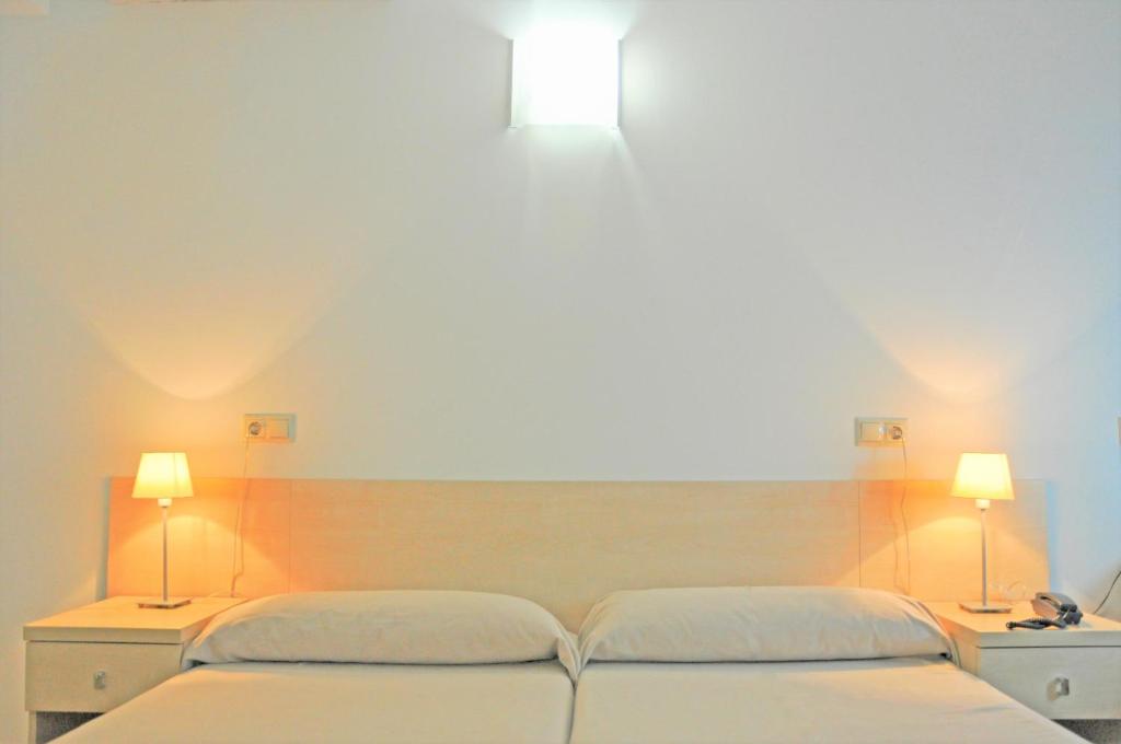 two beds in a room with two lights on the wall at Residencia Universitaria Sant Jordi in Tarragona