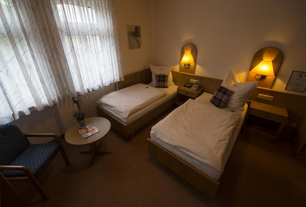 a hotel room with two beds and a chair at Hotel Dorheimer Hof in Friedberg