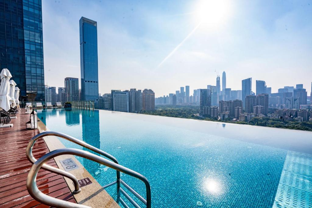 una piscina con vista sullo skyline della città sullo sfondo di Fraser Suites Shenzhen, Near Huaqiang North Business Zone and next to shopping mall complex, with direct subway access a Shenzhen