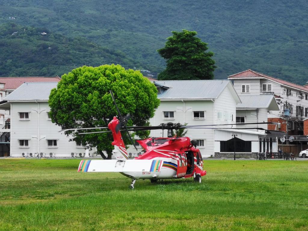 a red helicopter parked in a field in front of a building at Oak Garden in Hualien City