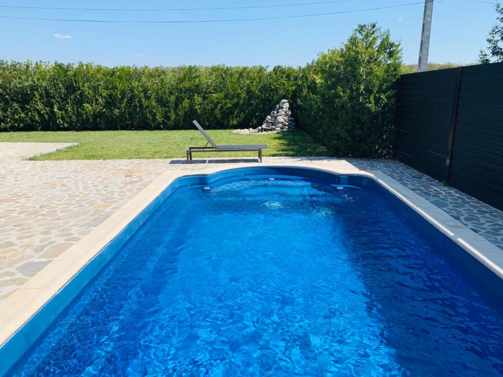 a blue swimming pool with a bench in a backyard at Luxury 3 Bedroom Pool Villa in Gulia