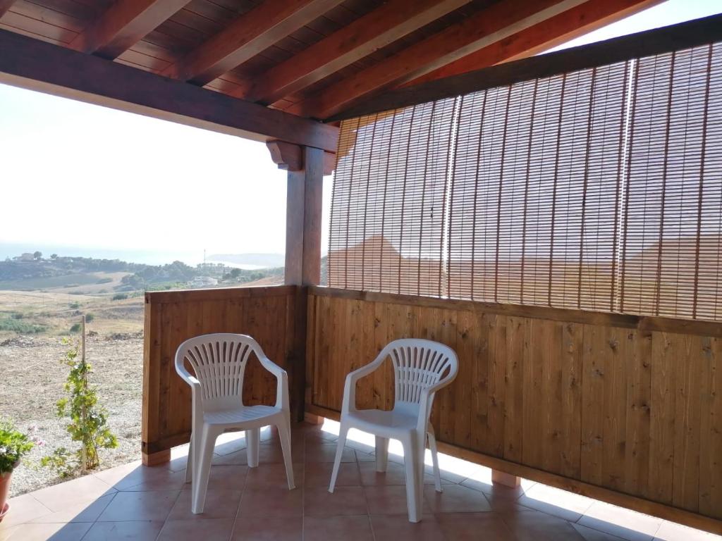 - deux chaises blanches sur une terrasse couverte avec vue dans l'établissement casa marino, à Montallegro