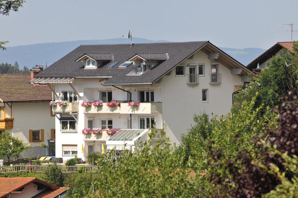 una casa blanca con flores en los balcones en Pension / FW Gästehaus Stern, en Bodenmais