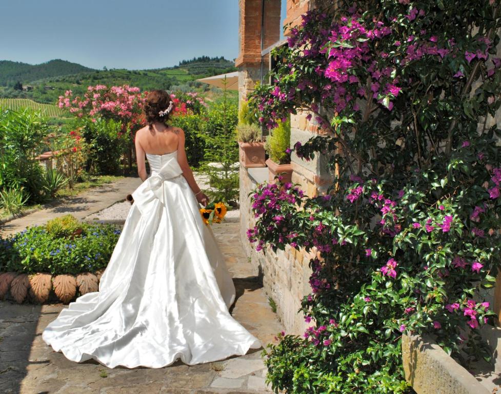 Eine Frau in einem Hochzeitskleid, die durch einen Garten geht. in der Unterkunft LA ROSA DEI VESPUCCI Historic Apartments in Greve in Chianti