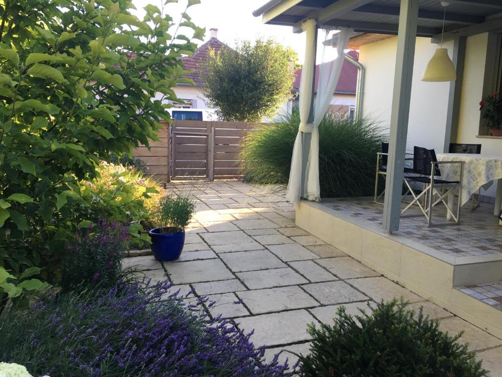 a garden with a patio with purple flowers at Szélrózsa apartmanház in Velence