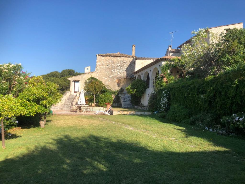 une grande maison avec une cour avec une personne assise dans l'herbe dans l'établissement La Petite Maison, à Saint-Paul-de-Vence