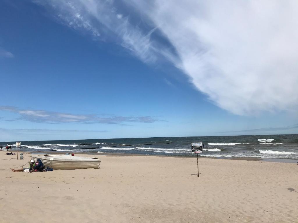 a boat sitting on a beach with the ocean at Residenz am Peeneplatz in Peenemünde