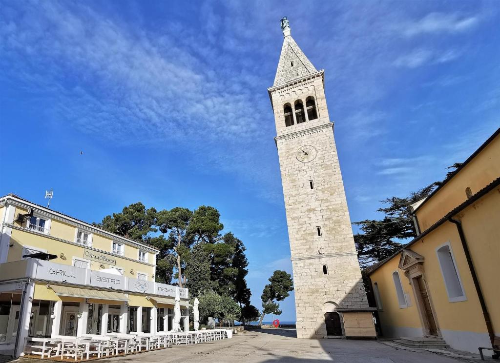 einen hohen Turm mit einer Uhr darüber in der Unterkunft STELLA deluxe SUPERIOR 5 star apartment, your piece of heaven by the sea & park, with sea view in Novigrad Istria