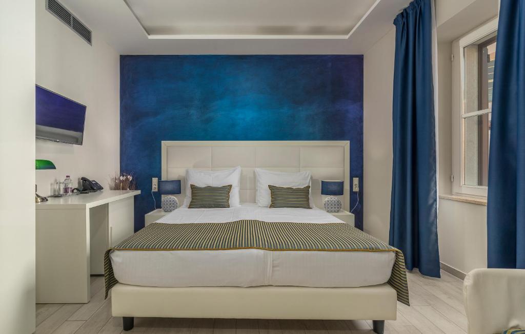 a bedroom with a large bed with a blue wall at Boutique Hotel Melissa in Poreč