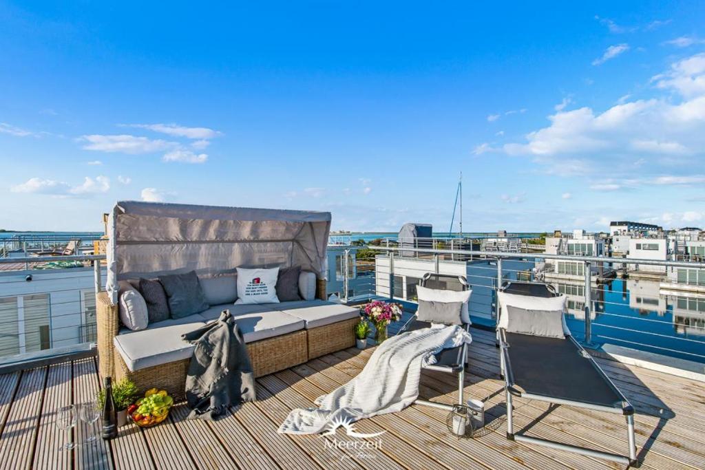 un balcón con 1 cama y 2 sillas en un barco en Treibholz: Meerblick, Dachterrasse, Bootsanleger, Badeleiter, Sauna en Olpenitz