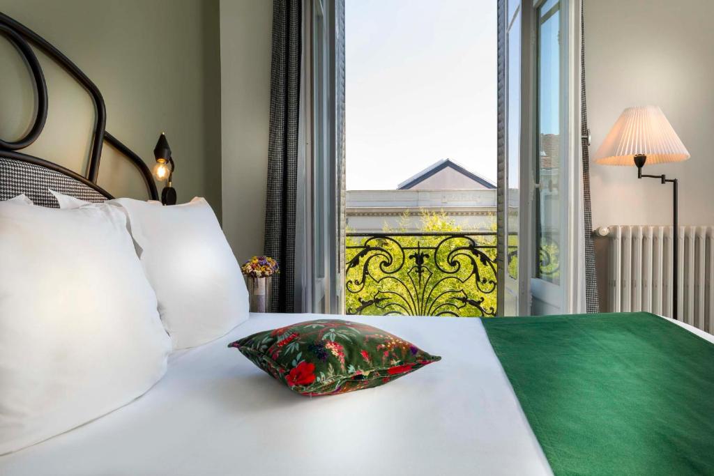 a bed with a pillow on it with a window at Hotel Saint Regis in Chalon-sur-Saône