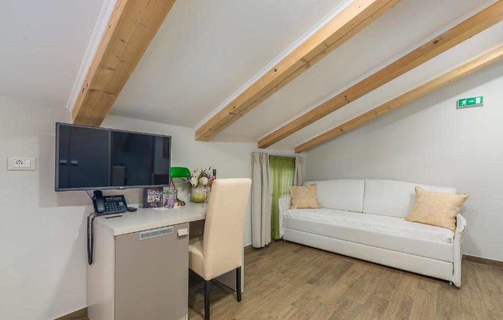 a room with a desk with a tv and a couch at Boutique Hotel Melissa in Poreč