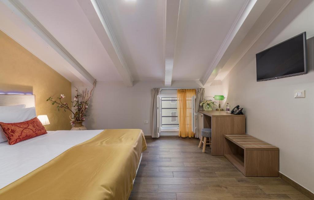a bedroom with a bed and a desk and a television at Boutique Hotel Melissa in Poreč