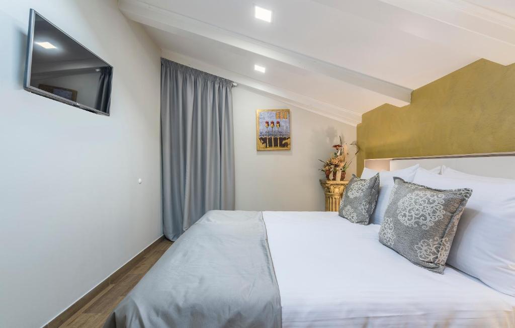a bedroom with a white bed and a television at Boutique Hotel Melissa in Poreč