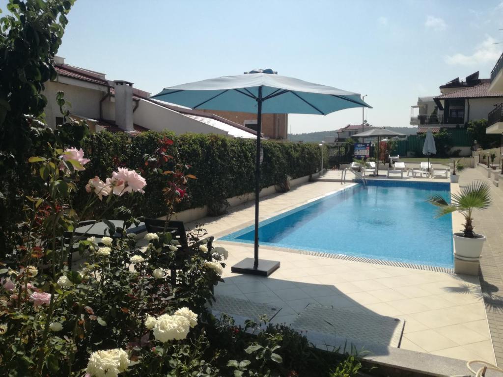 piscina con ombrellone e alcuni fiori di Apartments in Villas Apolon a Sozopol