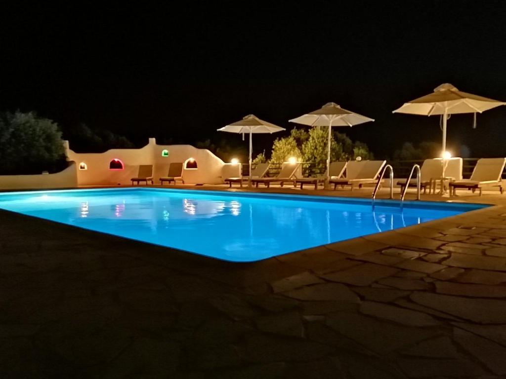 una piscina por la noche con sillas y sombrillas en Cavo Plako Villas, en Palaikastro
