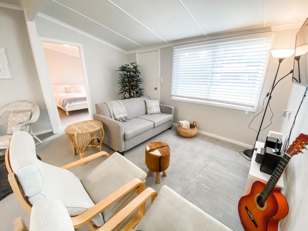 sala de estar con sofá y guitarra en Frangipani Cottage, en North Haven