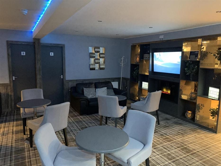 un soggiorno con tavoli, sedie e TV di The Davron Hotel a Fraserburgh