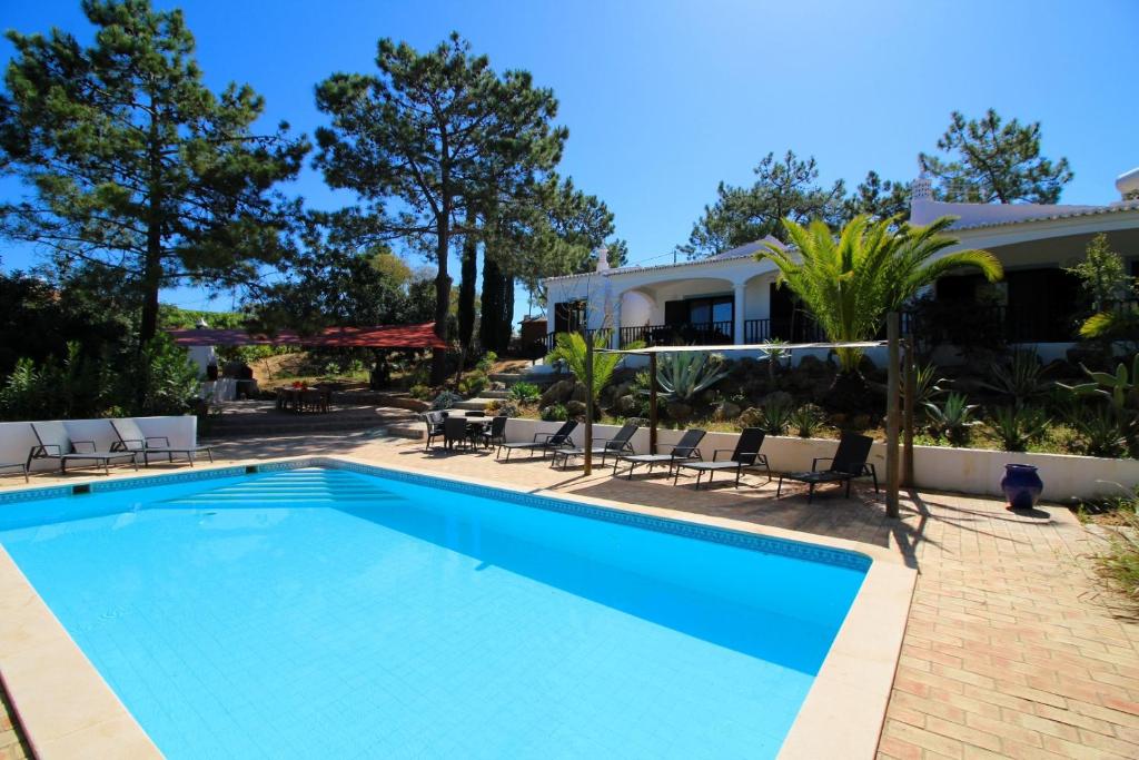 uma piscina com cadeiras e uma casa em Casa Palmeiras Luxury Tranquil area BBQ Large Pool em Carvoeiro