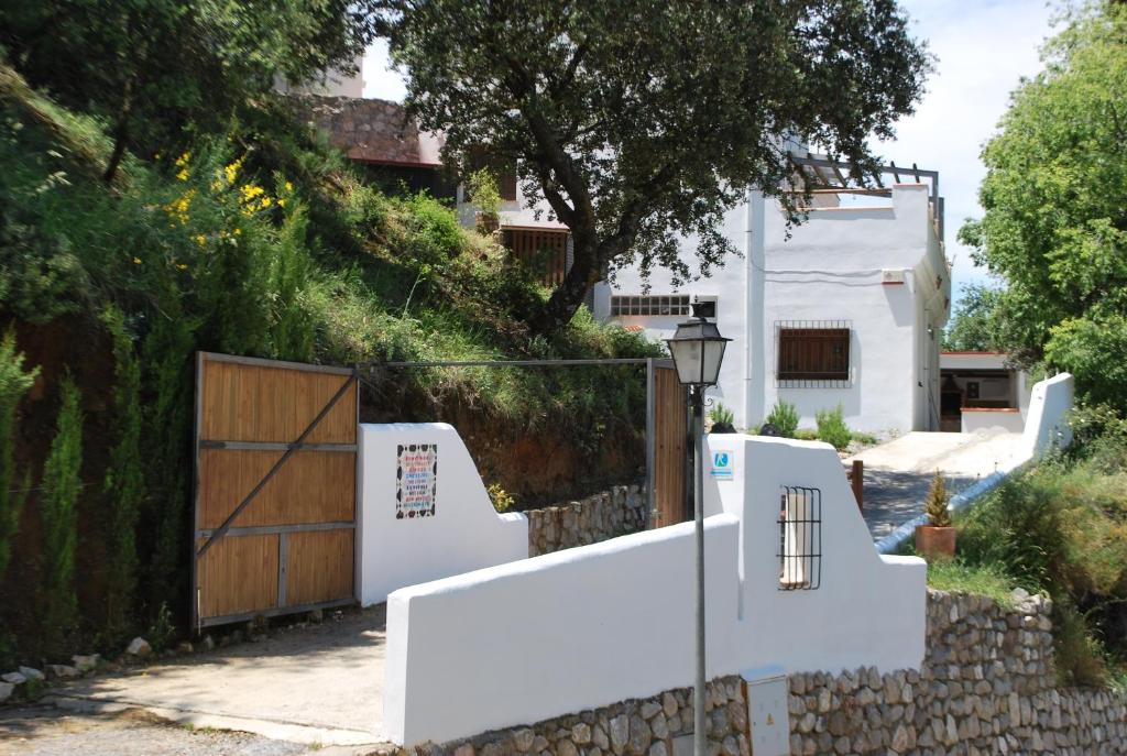 a white fence with a wooden gate and a house at Encinar de Aguas Blancas in Dúdar