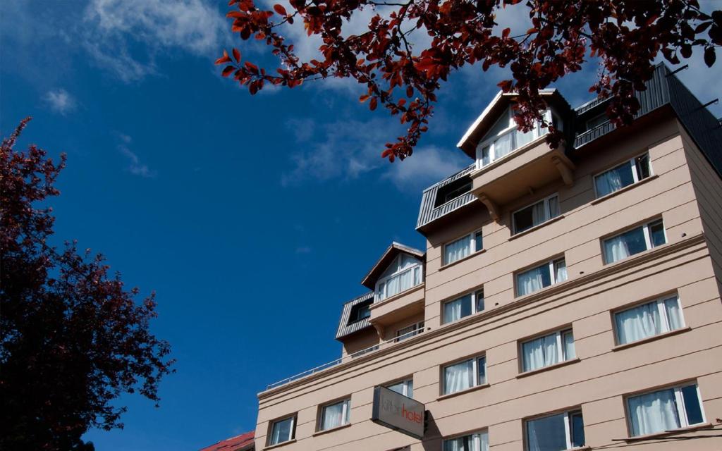 a tall building with a blue sky in the background at Hotel Kilton in San Carlos de Bariloche