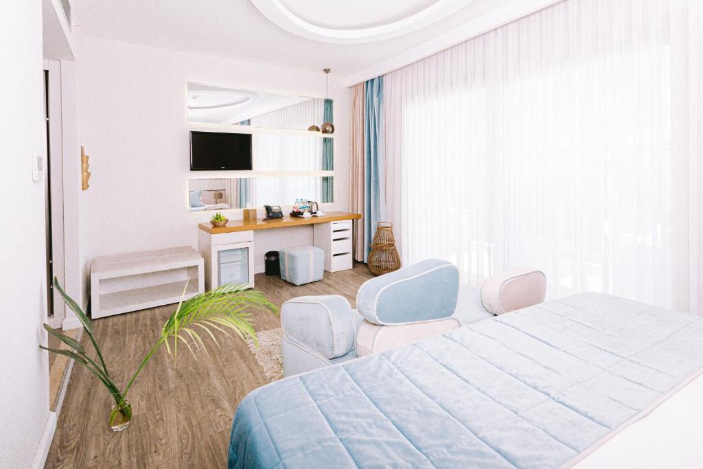a white bedroom with a bed and two chairs at Ilica Hotel Spa & Wellness Resort in Çeşme