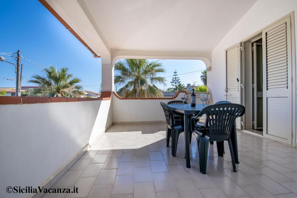 uma sala de jantar com uma mesa e cadeiras numa varanda em House Calabernardo Sea Beach - Sicilia Vacanza em Calabernardo
